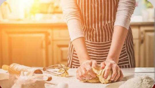 Mãos preparando massa artesanal sobre a bancada da cozinha